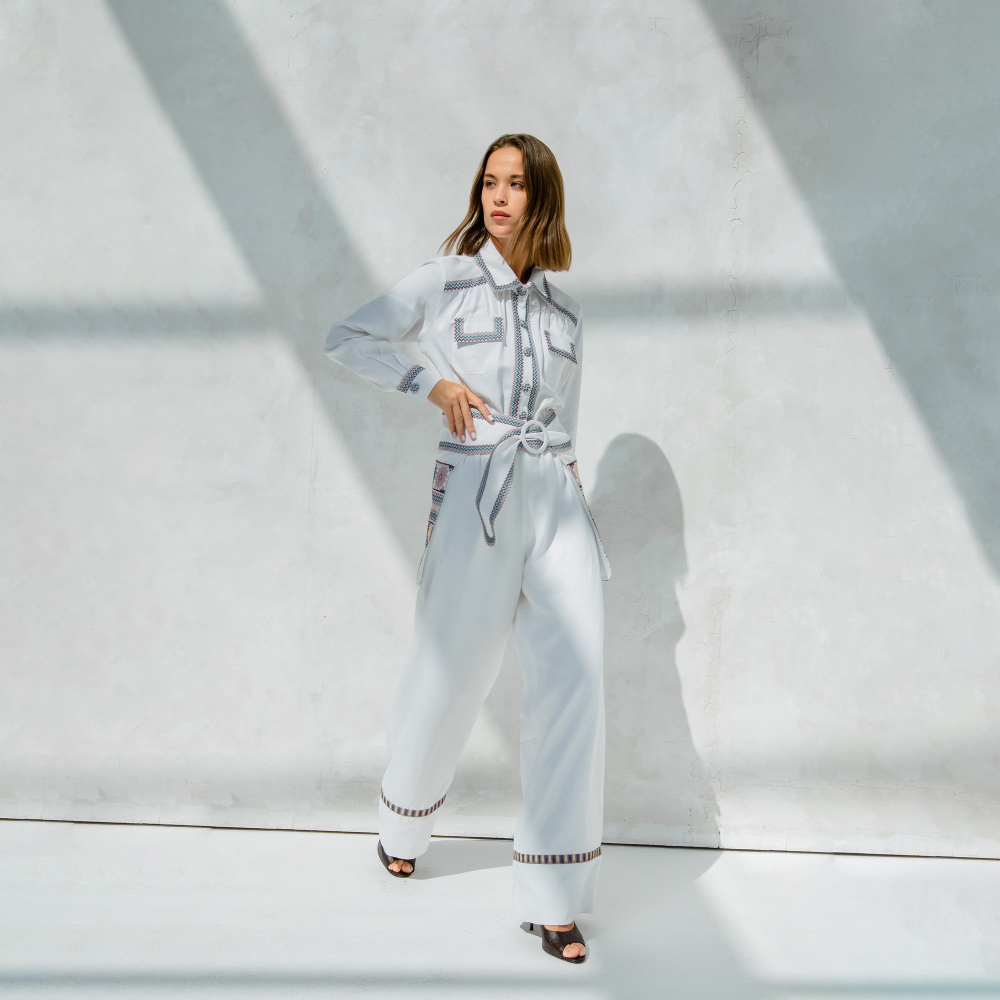 KORONEIKI White Linen Embroidered Long Sleeve Jumpsuit with Separate Waist Belt Piece by Lara Ali